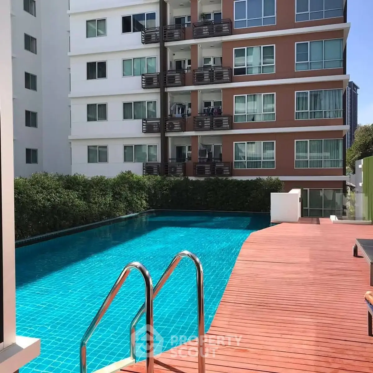 Modern apartment building with inviting pool and wooden deck, perfect for relaxation.