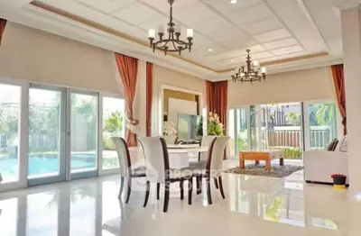 Luxurious living room with pool view, elegant chandeliers, and floor-to-ceiling windows.