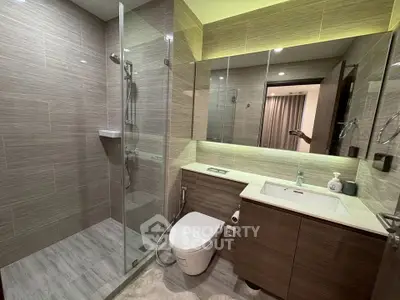 Modern bathroom with glass shower and sleek vanity in contemporary apartment.