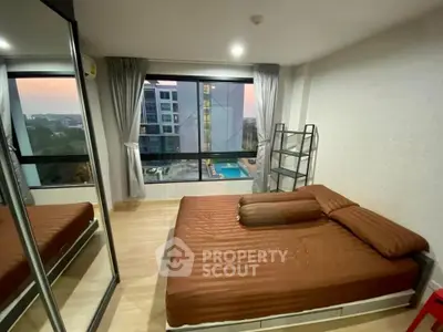 Modern bedroom with large window offering stunning city view and pool glimpse, featuring sleek mirrored wardrobe.