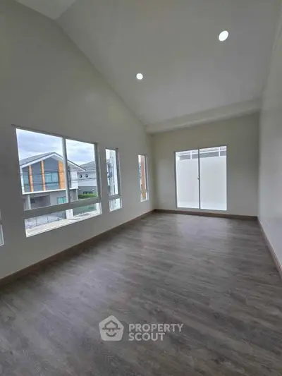 Spacious modern room with large windows and high ceiling, perfect for natural light.