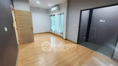 Spacious modern room with wooden flooring and large windows for natural light.