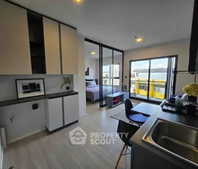 Modern open-layout apartment with sleek kitchen and spacious bedroom, featuring large windows and city views.