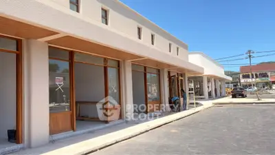 Modern commercial building exterior with large glass windows and ample parking space.