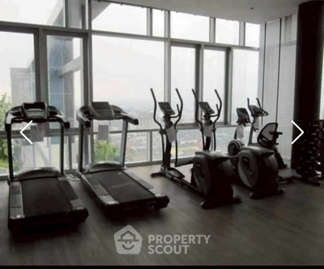 Modern gym with cardio equipment and city view in luxury apartment building.