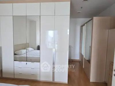 Spacious bedroom with mirrored wardrobe and wooden flooring