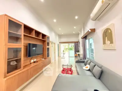 Spacious modern living room with sleek furniture and large TV, perfect for relaxation and entertainment.