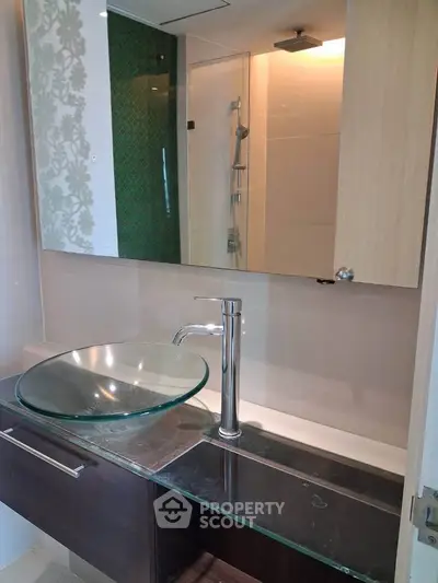 Modern bathroom with glass sink and stylish fixtures in a contemporary apartment.