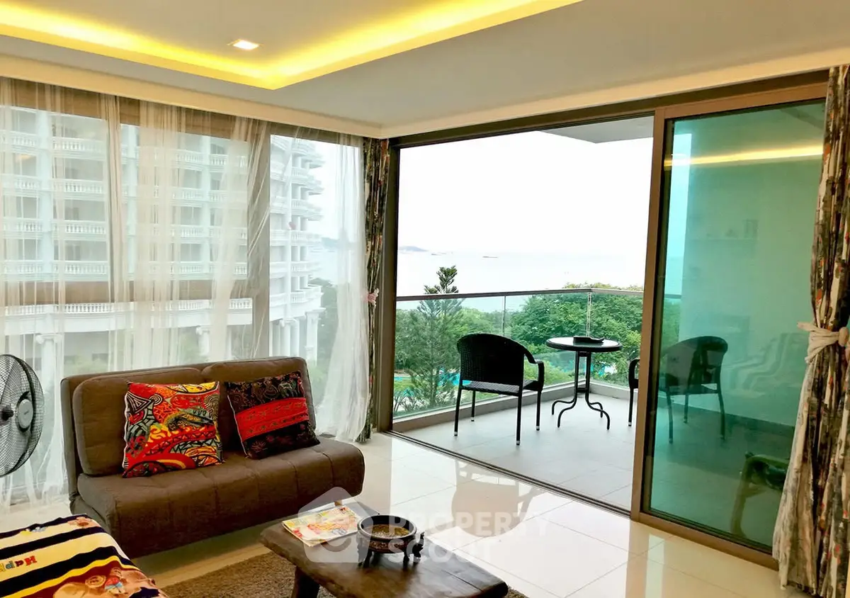 Spacious living room with balcony offering stunning ocean view in modern apartment.