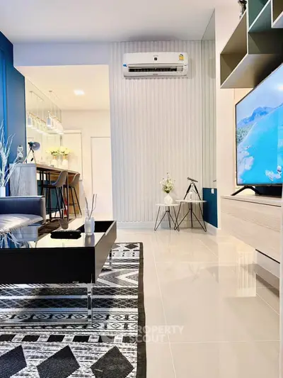 Modern living room with stylish decor and open layout, featuring a wall-mounted TV and sleek furniture.