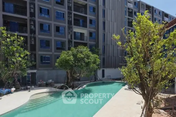 Modern apartment building with a stylish outdoor pool and lush greenery.