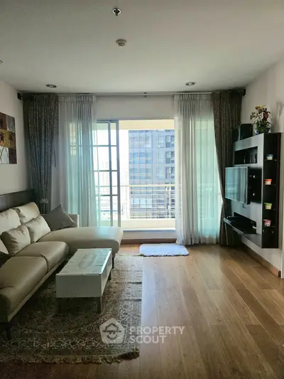 Spacious living room with modern decor and large windows offering city views.