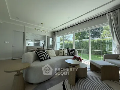 Luxurious living room with modern furniture and large windows overlooking a lush garden.