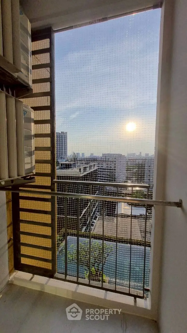 Stunning city view from high-rise balcony with pool and sunset backdrop.