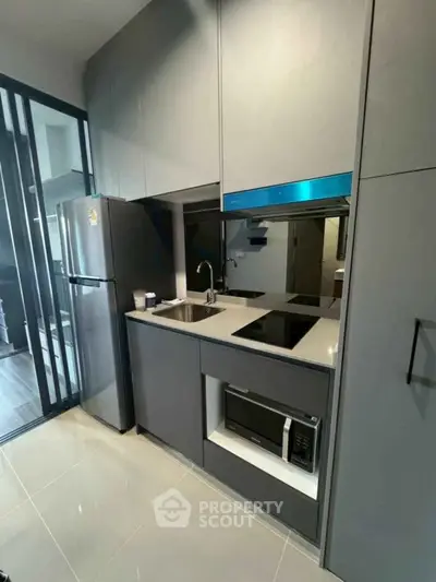 Modern compact kitchen with sleek cabinetry and built-in appliances in a stylish apartment.