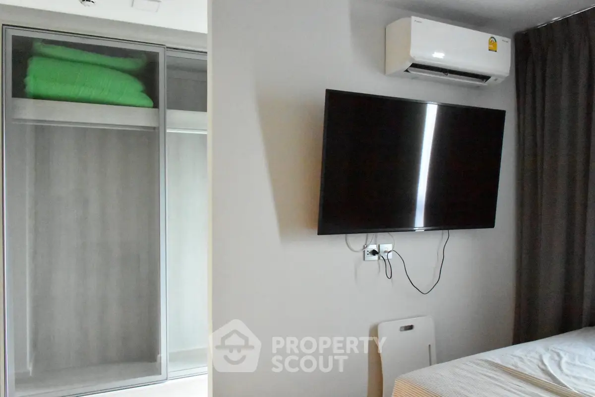 Modern bedroom with wall-mounted TV and air conditioner, featuring sleek wardrobe design.
