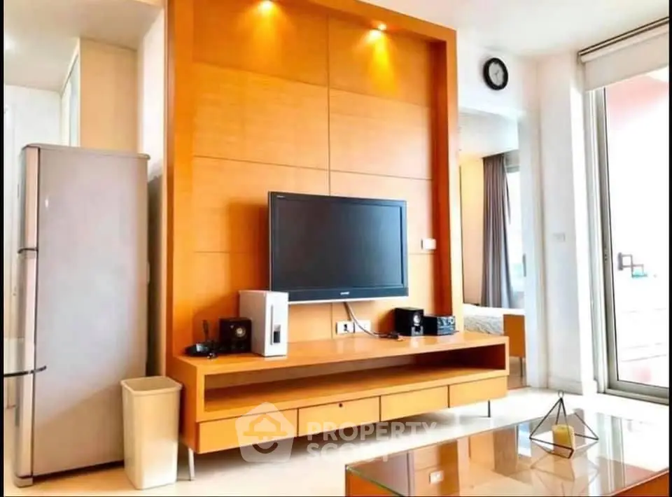 Modern living room with sleek TV unit and large fridge, bright and inviting space.