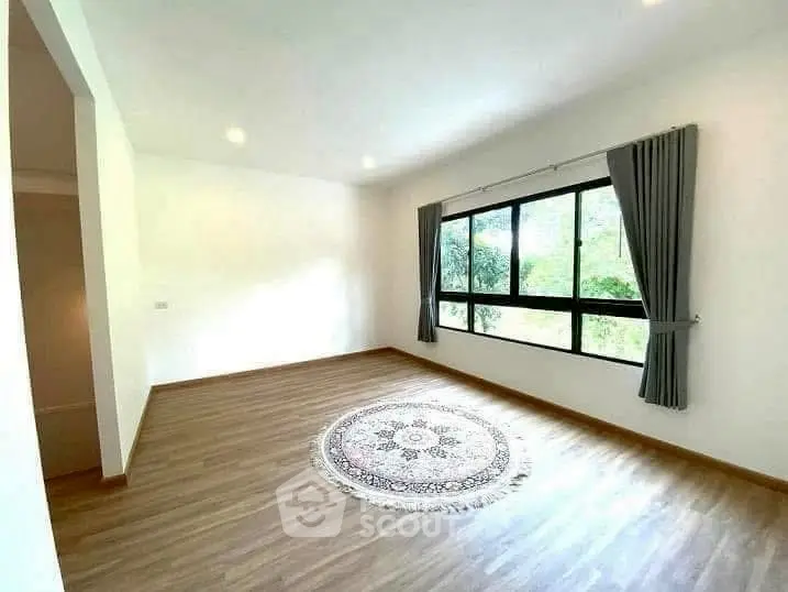 Spacious empty room with large window and wooden flooring, ideal for customization.
