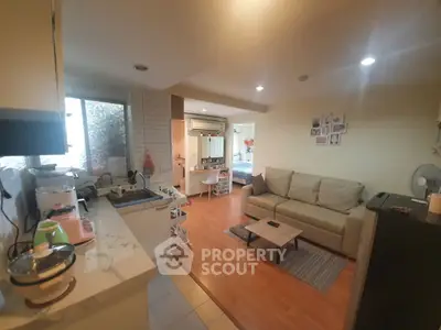 Cozy open-layout living room with kitchen, featuring modern decor and warm lighting.
