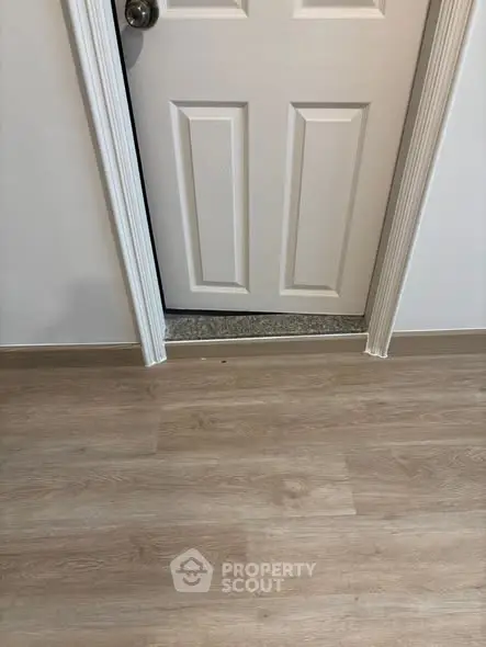 Modern interior with wooden flooring and white door, showcasing sleek design and quality materials.