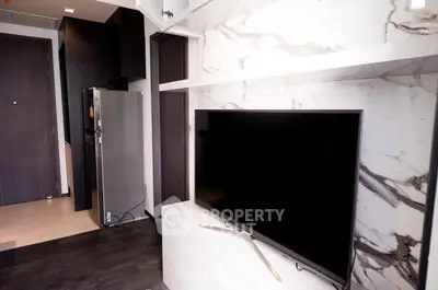 Modern apartment interior with sleek TV setup and stylish kitchen area.