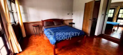 Spacious bedroom with wooden flooring and large windows for natural light.