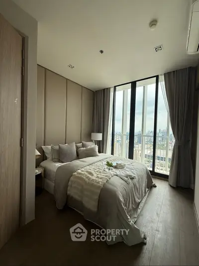 Luxurious bedroom with floor-to-ceiling windows and city view, elegant decor and cozy ambiance.