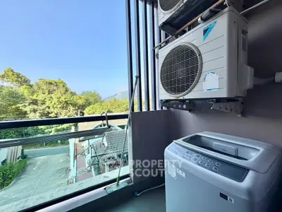 Modern balcony with scenic view and laundry area featuring washing machine and air conditioning unit.
