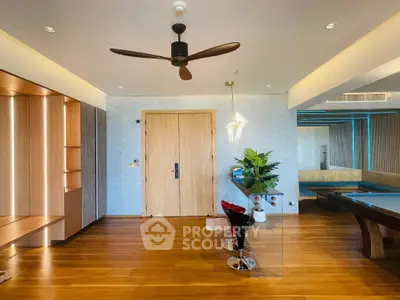 Modern living room with wooden flooring, stylish ceiling fan, and elegant lighting.