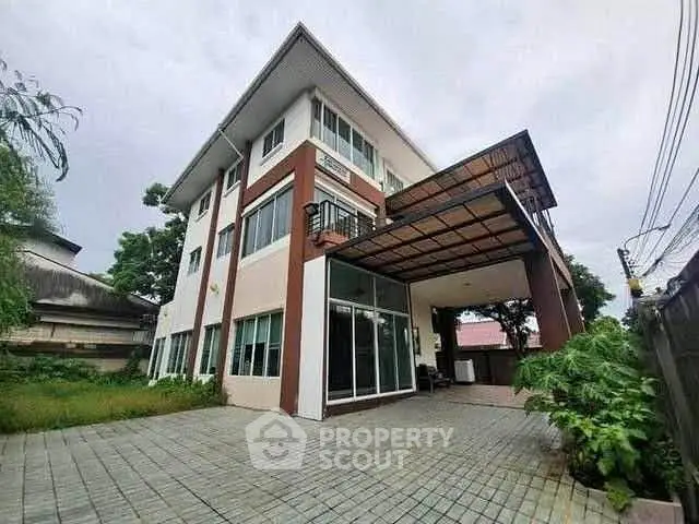 Spacious modern three-story house with large driveway and lush greenery.