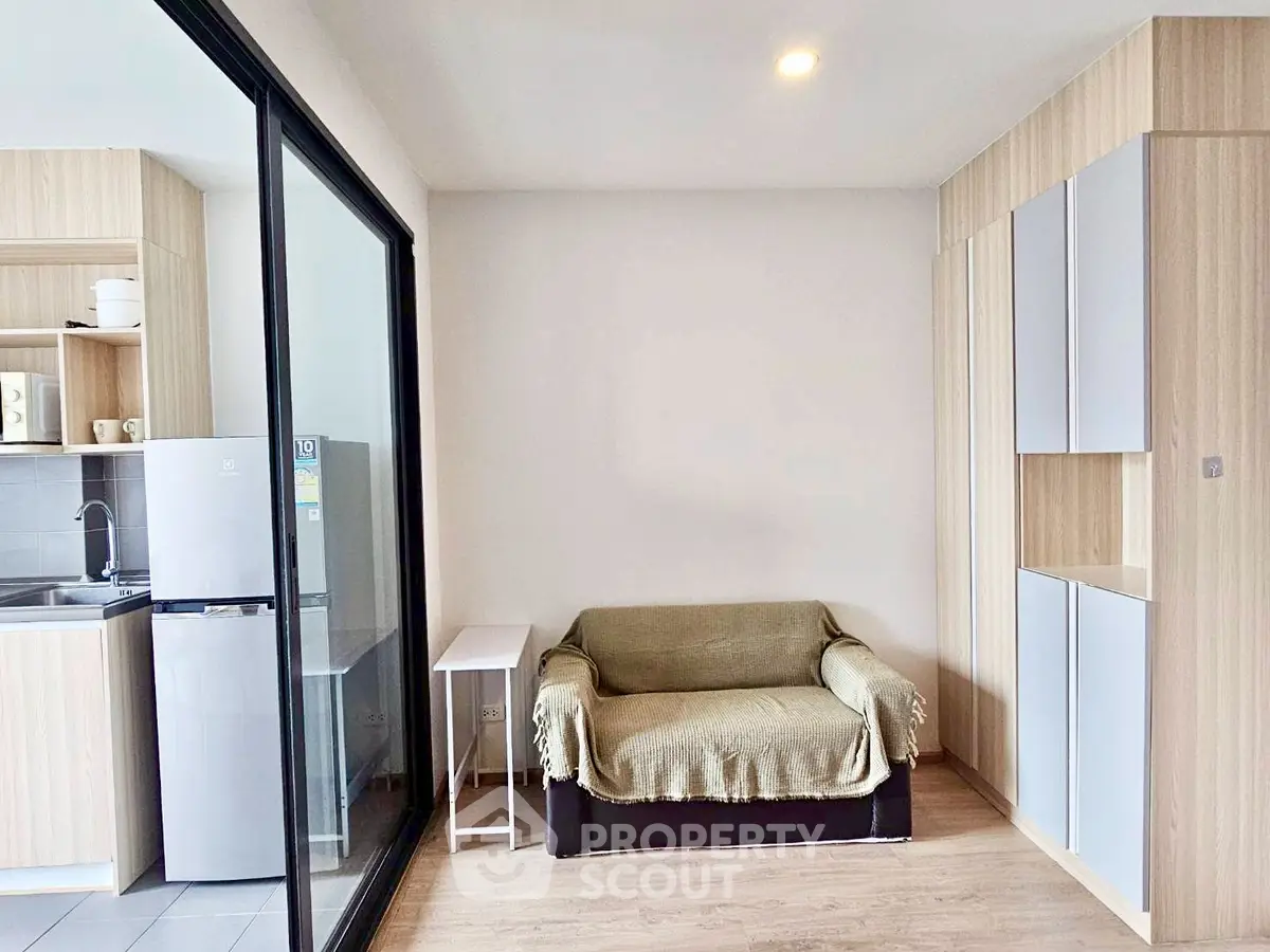 Modern compact living room with kitchenette and cozy seating area in a stylish apartment.