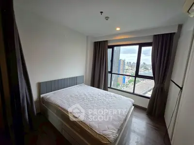 Modern bedroom with city view and large window, featuring a comfortable bed and stylish decor.