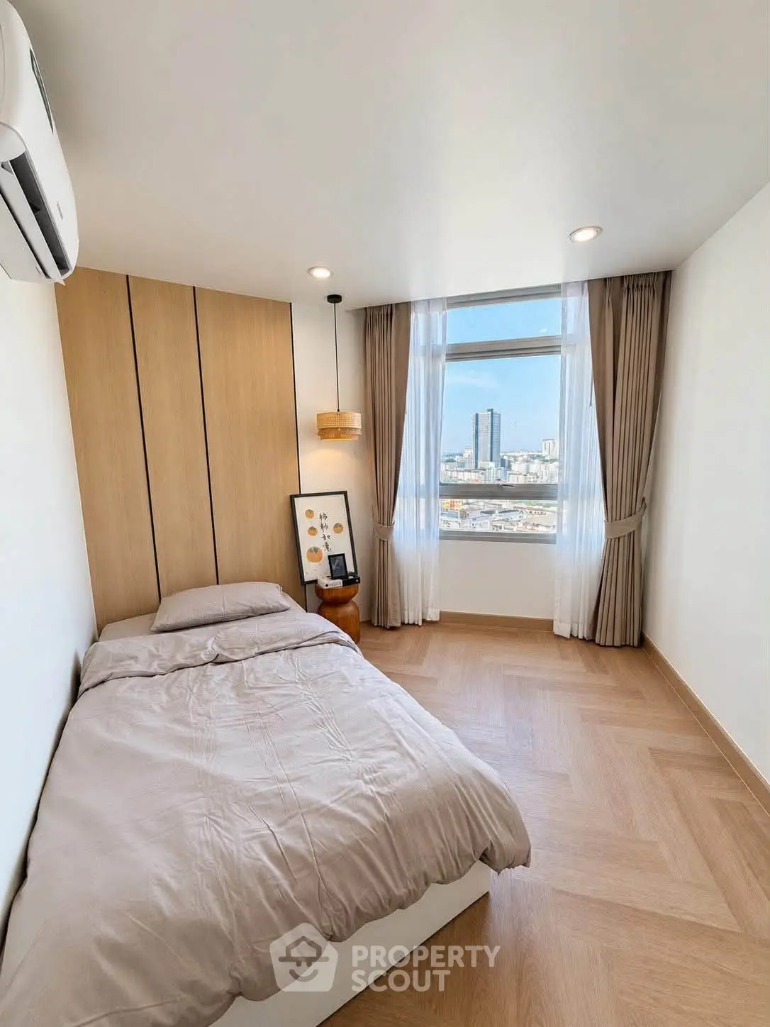 Modern bedroom with city view, wooden flooring, and cozy decor in a high-rise apartment.