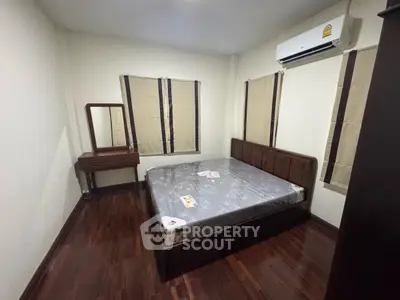 Cozy bedroom with wooden flooring and air conditioning, featuring a bed and vanity set.