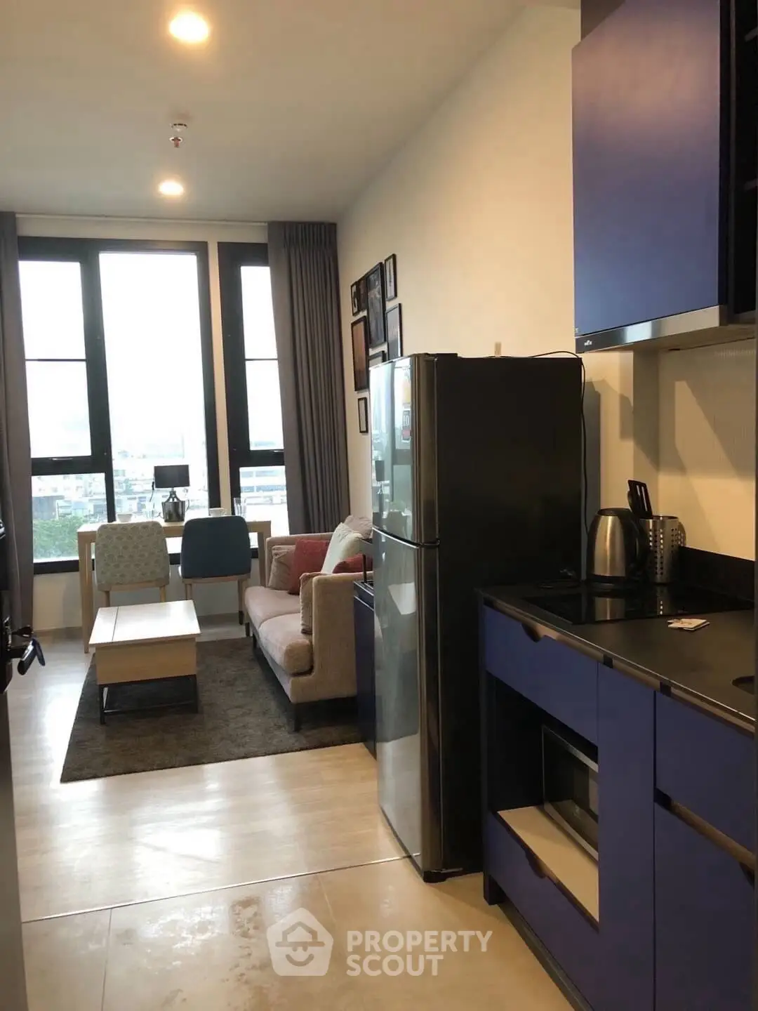 Modern open-layout kitchen and living room with stylish furniture and large windows.