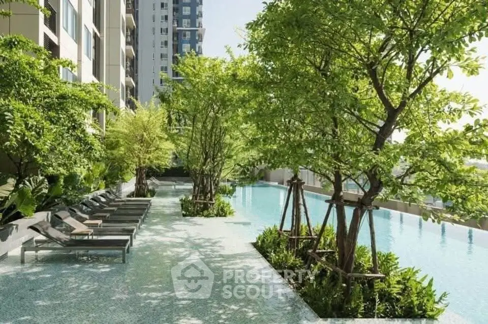 Luxurious poolside area with lush greenery and modern lounge chairs in a high-end residential complex.