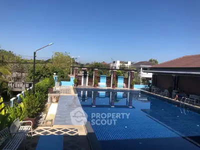 Luxurious outdoor pool area with clear blue water and lush greenery, perfect for relaxation and leisure.