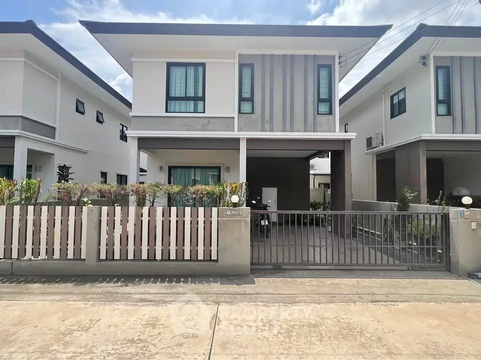 Modern two-story house with sleek design and gated front yard in a suburban neighborhood.