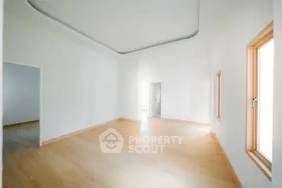 Spacious empty room with wooden flooring and large windows, perfect for customization.