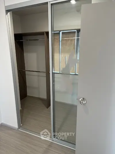 Spacious walk-in closet with sliding mirrored doors in modern apartment