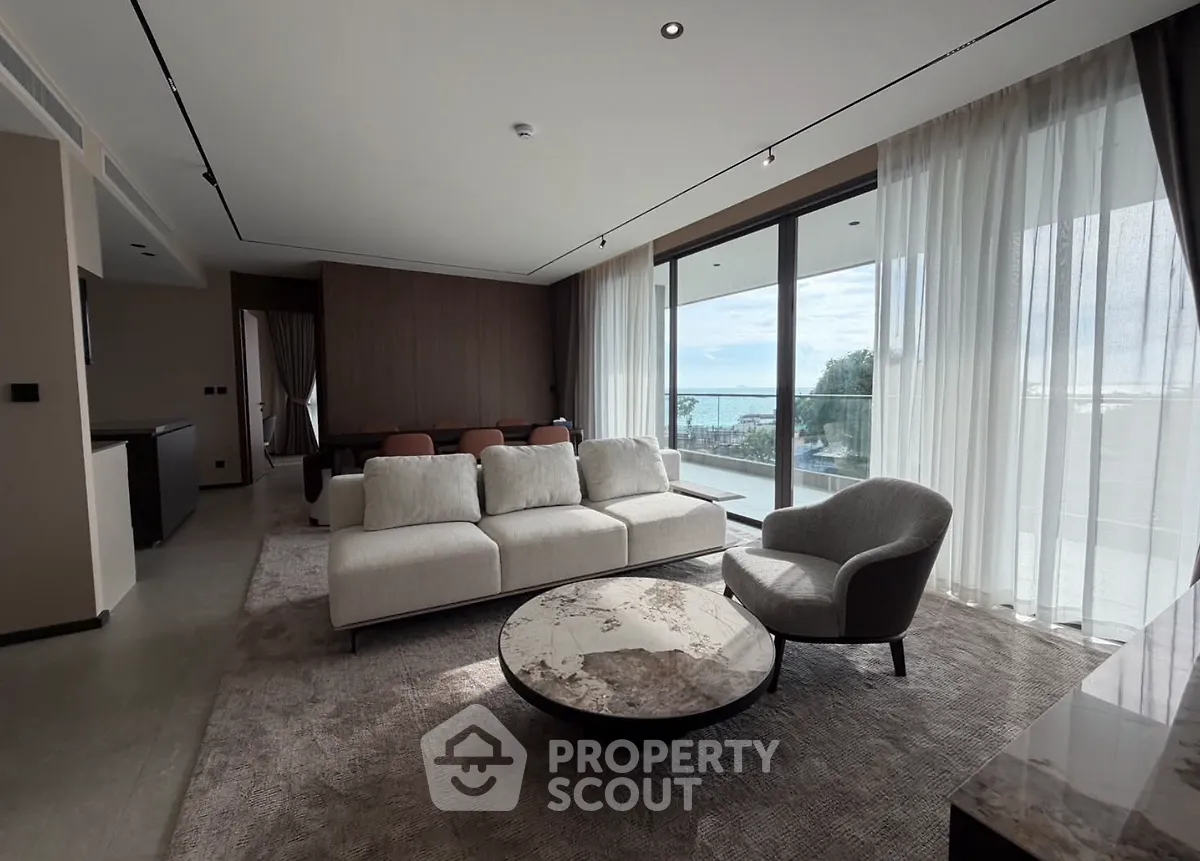 Luxurious living room with modern furniture and stunning sea view from large windows.