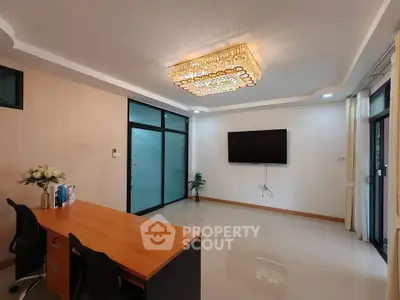 Spacious modern office with elegant chandelier and large TV, ideal for professional settings.