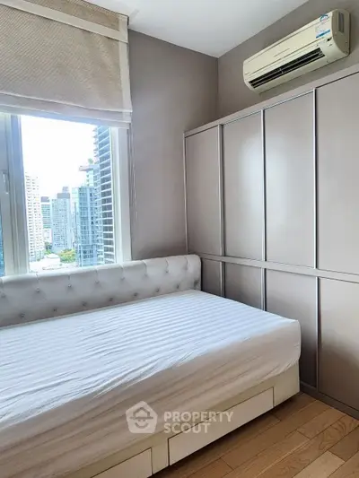 Modern bedroom with city view, featuring sleek wardrobe and air conditioning, perfect for urban living.