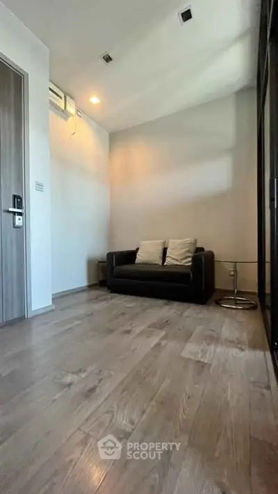 Modern living room with sleek design and wooden flooring, featuring a cozy sofa and stylish lighting.