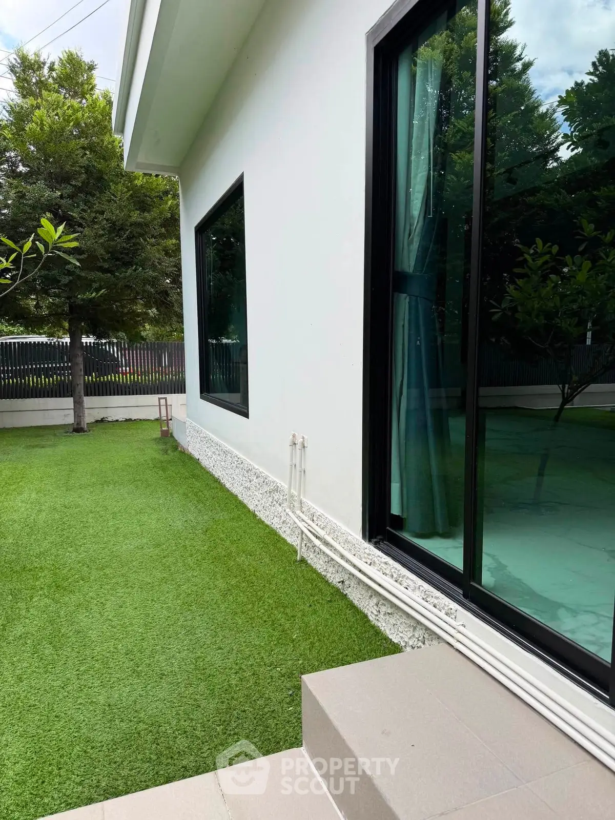 Modern home exterior with lush green lawn and large windows, perfect for natural light lovers.