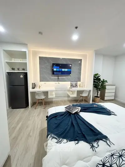 Modern bedroom with stylish decor and smart TV, featuring cozy seating area and sleek flooring.