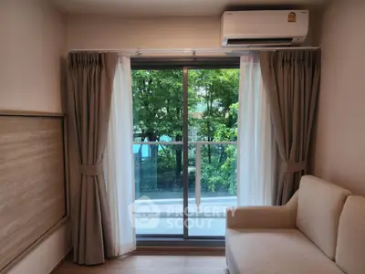 Cozy living room with large window and garden view, featuring a comfortable sofa and air conditioning.