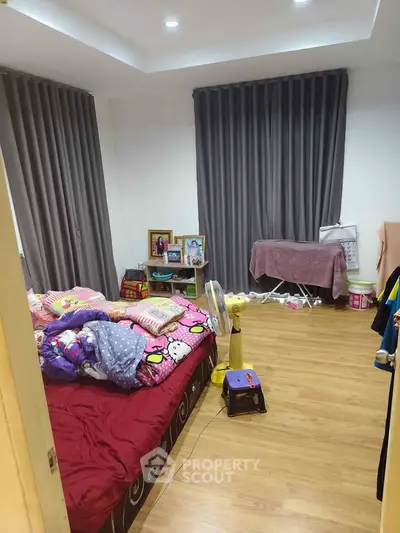 Cozy bedroom with wooden flooring and modern curtains, ideal for a comfortable living space.