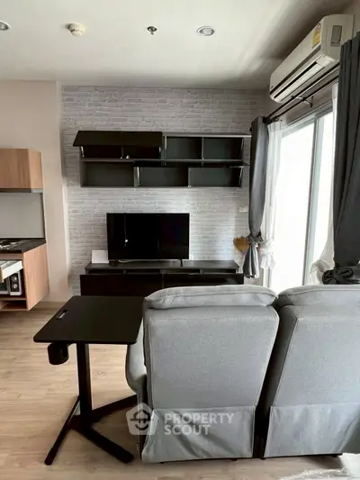 Modern living room with sleek furniture and entertainment center, featuring large windows and stylish decor.