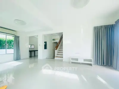 Spacious and bright living room with modern staircase and large windows